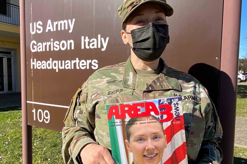 A soldier holds up a magazine while posing for a photo.