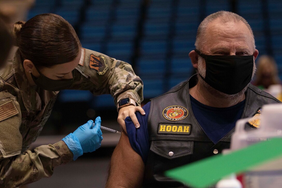 A service member administers the COVID-19 vaccine to a civilian.