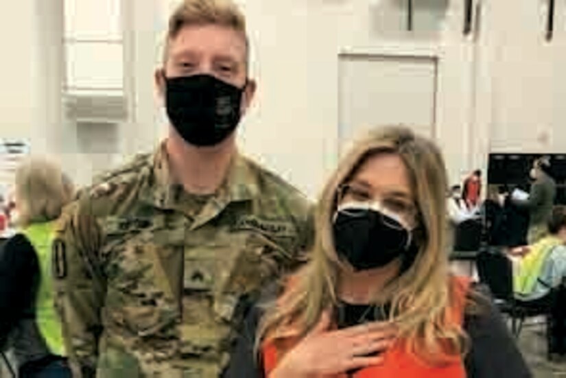 A soldier stand next to a woman as they pose for a photo.