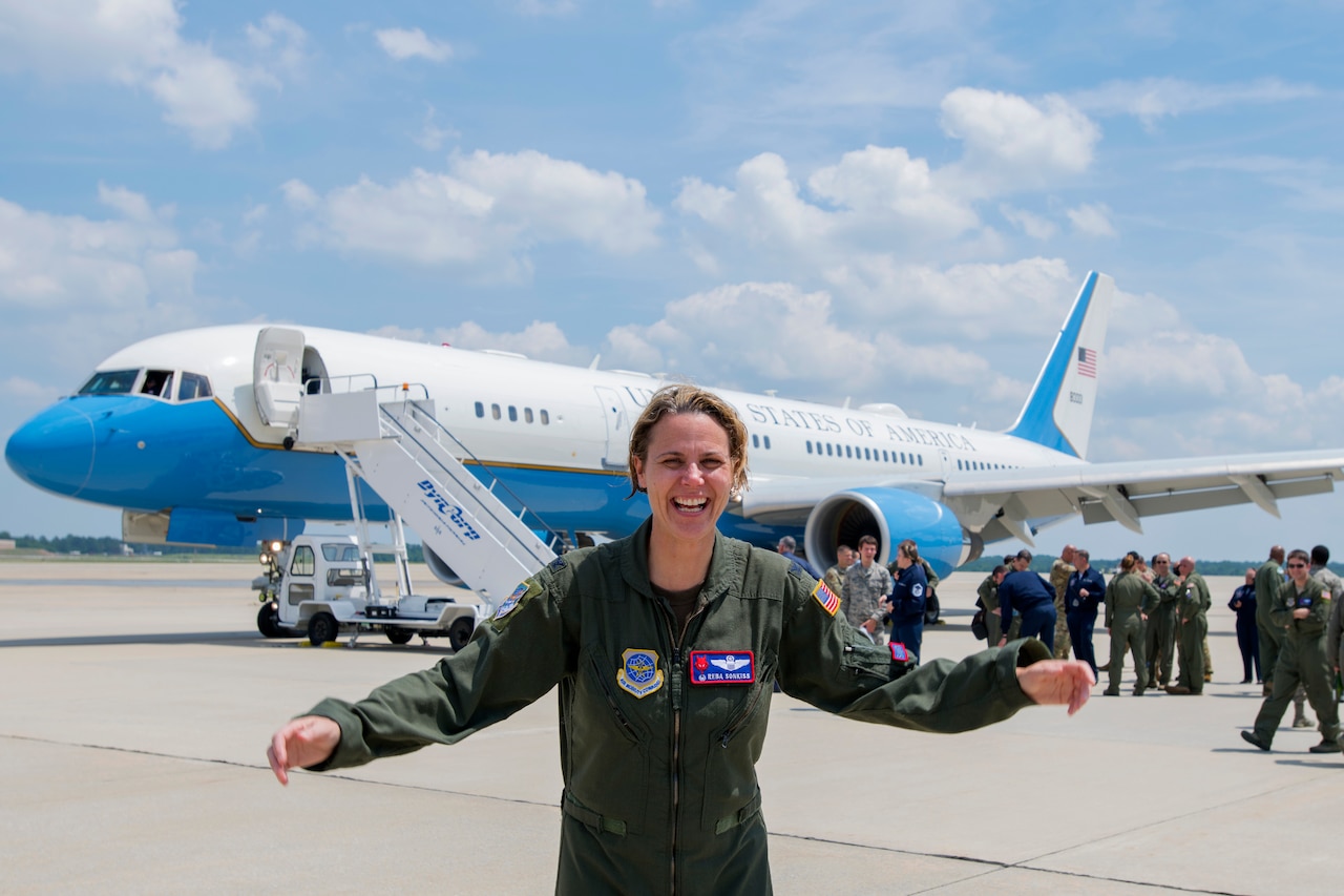 A young Air Force colonel shows the results of a wet down after her final flight aboard the blue and white aircraft behind her.