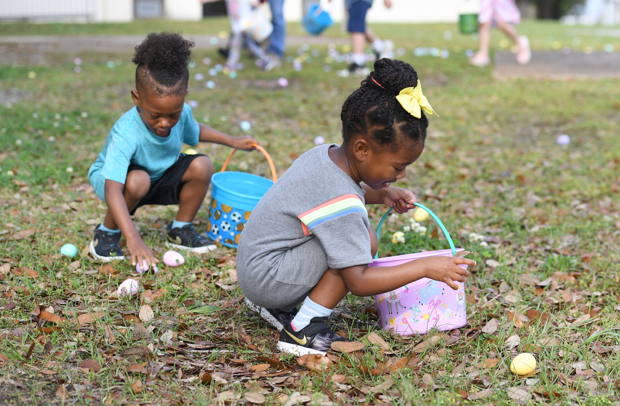 Kylan and Caris Campbell, children of U.S. Air Force Maj. Alecia Campbell, 81st Contracting Squadron commander, pick up Easter eggs during Keesler's Eggstravaganza at the marina park at Keesler Air Force Base, Mississippi, March 27, 2021. The 81st Force Support Squadron hosted the event for military children. (U.S. Air Force photo by Kemberly Groue)
