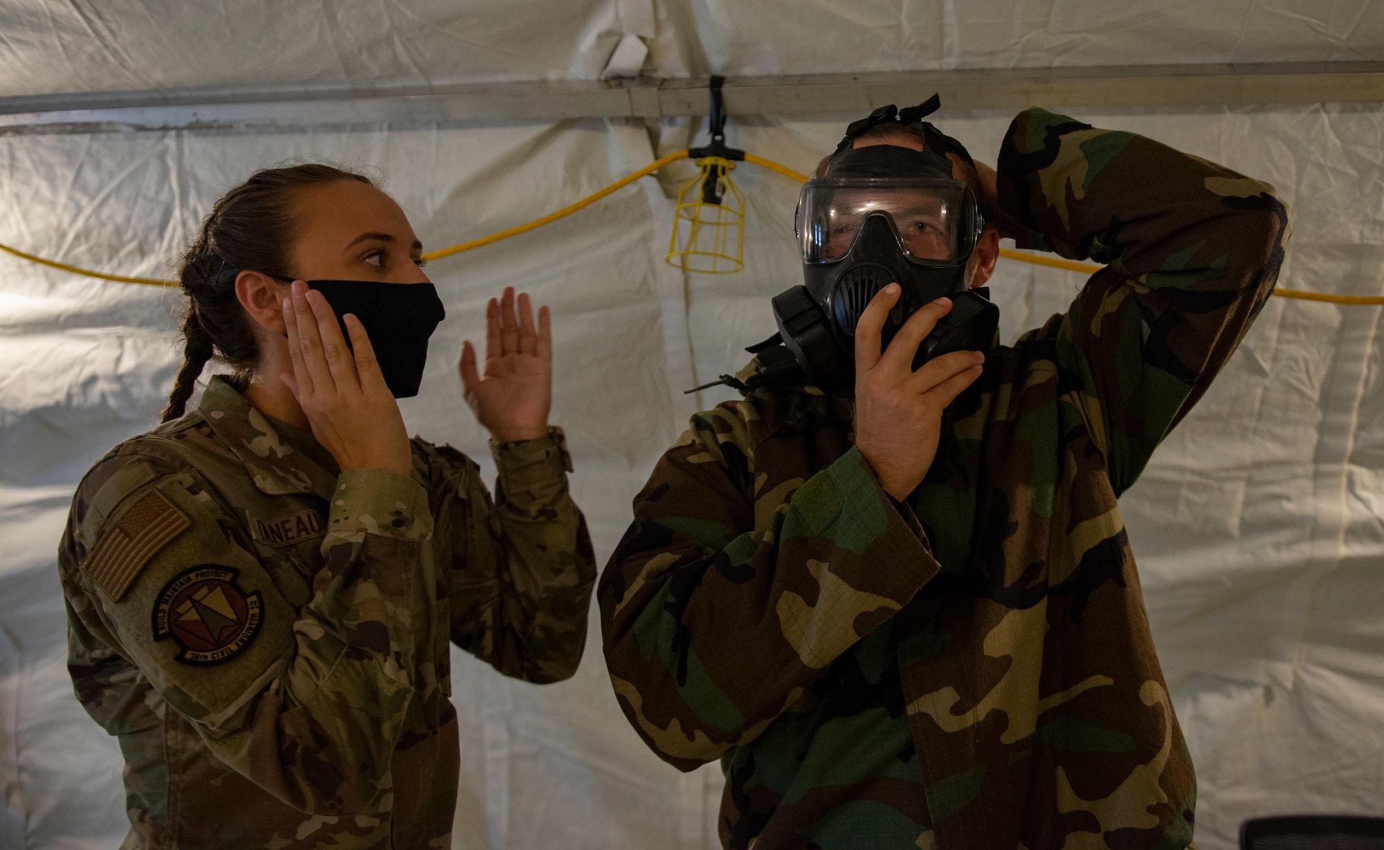 U.S. Air Force Airman 1st Class Maria Daneault, an emergency management apprentice assigned to the 36th Civil Engineer Squadron, instructs U.S. Air Force Senior Airman James Fink how to don his mask during Chemical, Biological, Radiological, Nuclear and Explosives defense training at Andersen Air Force Base, Guam, March 25, 2021.