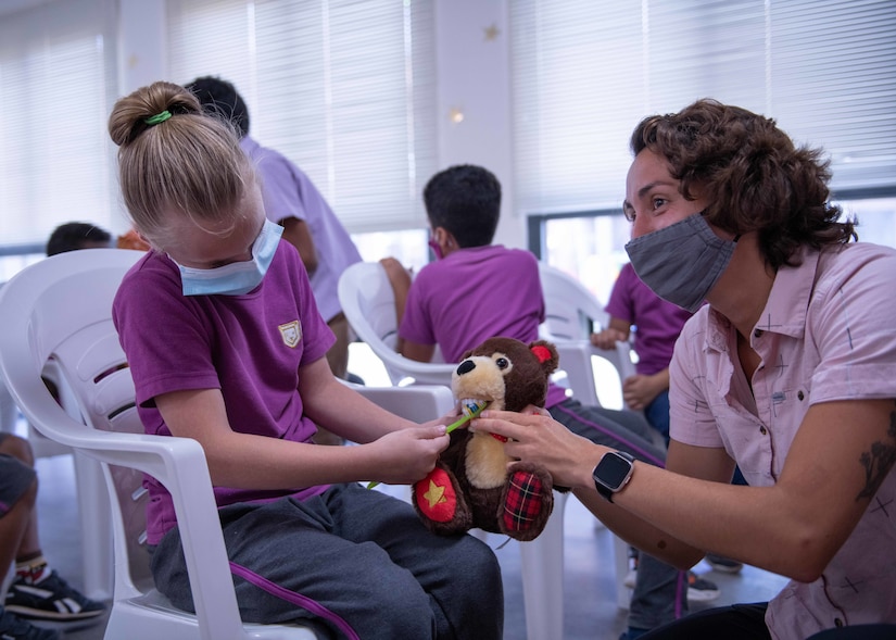 A child shows U.S. Army Cpl. Hannah Sivak, a medic assigned to Civil Affairs East Africa Southern European Task Force Africa (CA-EA SETAF-AF) functional specialty team in support of Combined Joint Task Force-Horn of Africa (CJTF-HOA), how she brushes teeth on a toy bear during an oral health class at the International School of Africa, Arta, Djibouti, March 23, 2021. The CA-EA SETAF-AF team is composed of dentists, veterinarians, medics, and other medical specialties, giving them the unique capability to deliver and share educational and clinical expertise throughout the Horn of Africa.