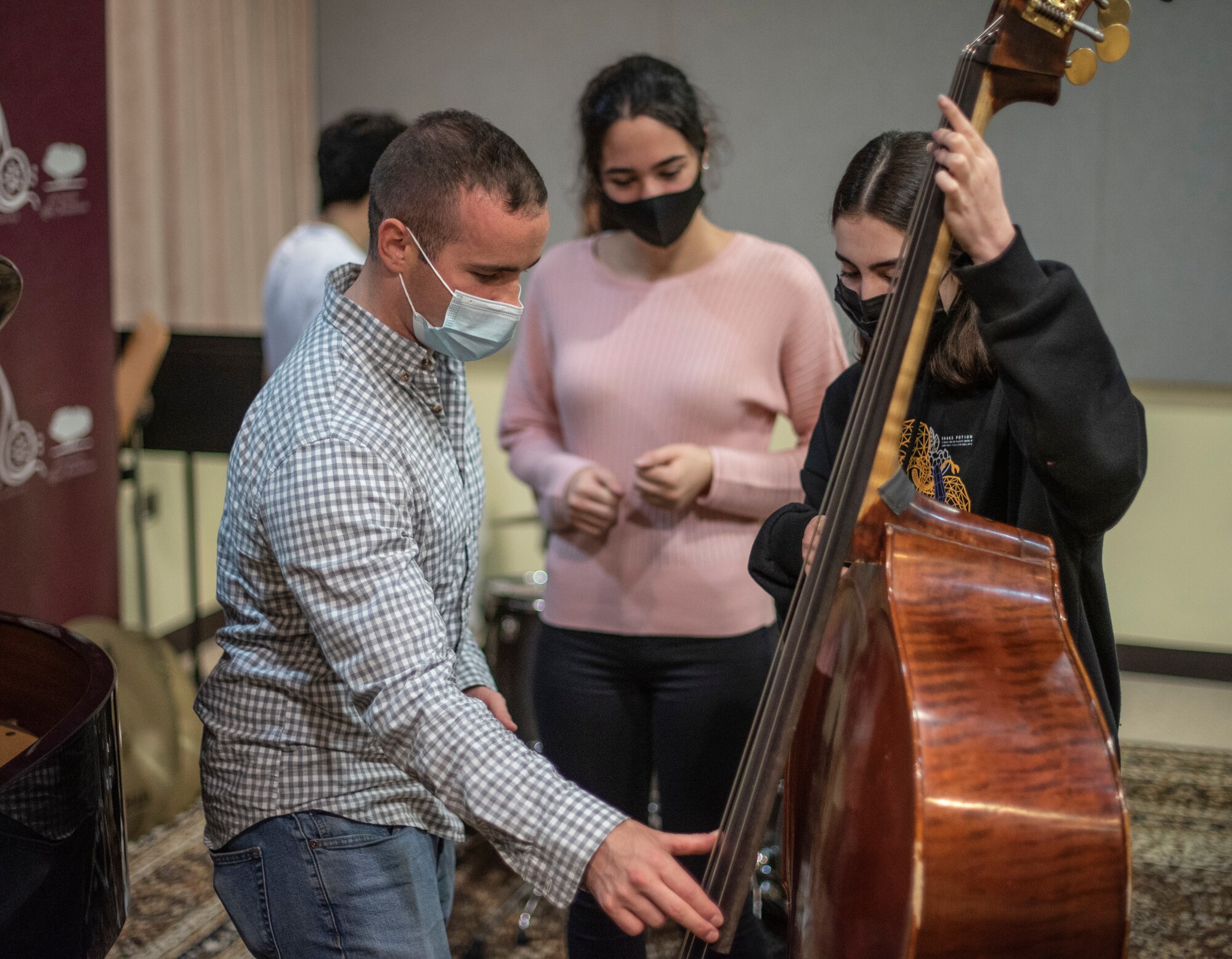 Senior Airman Dominic Sbrega, U.S. Air Forces Central Band musician, instructs a Qatar Music Academy student on the bass during an engagement at the academy in Doha, Qatar, March 24, 2021. The AFCENT Band perform and tour in small ensembles throughout the region to promote positive troop morale, diplomacy and outreach to host-nation communities. (U.S. Air Force photo by Tech. Sgt. Travis Edwards)