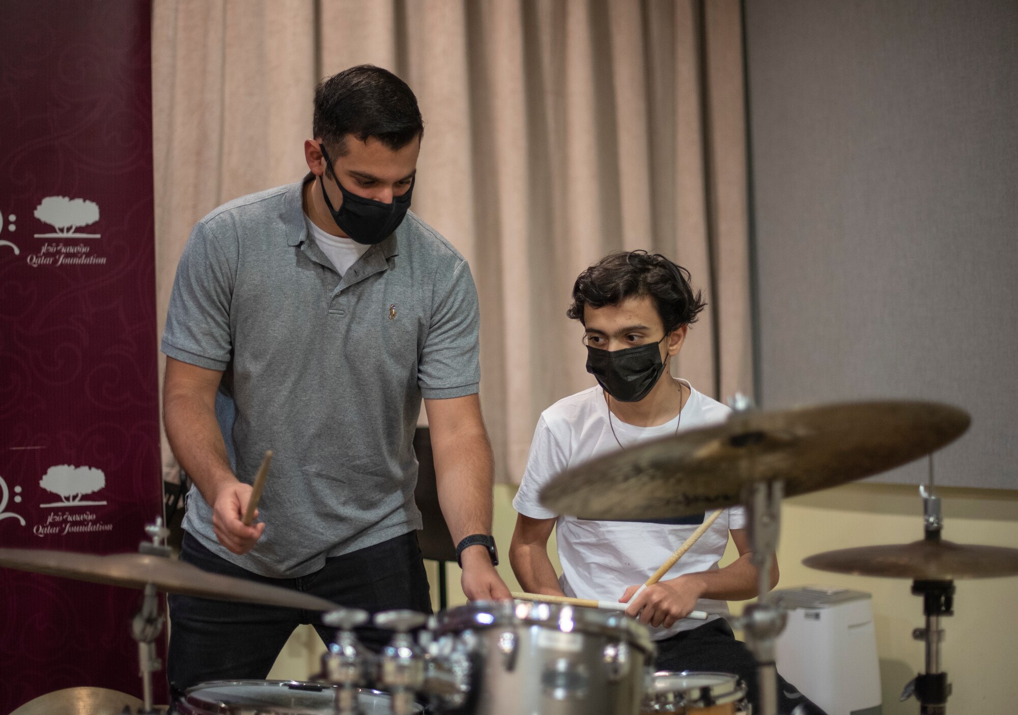 Staff Sgt. Michael Coletti, U.S. Air Forces Central Band musician, instructs a Qatar Music Academy student on jazz percussion during an engagement at the academy in Doha, Qatar, March 24, 2021. The AFCENT Band perform and tour in small ensembles throughout the region to promote positive troop morale, diplomacy and outreach to host-nation communities. (U.S. Air Force photo by Tech. Sgt. Travis Edwards)