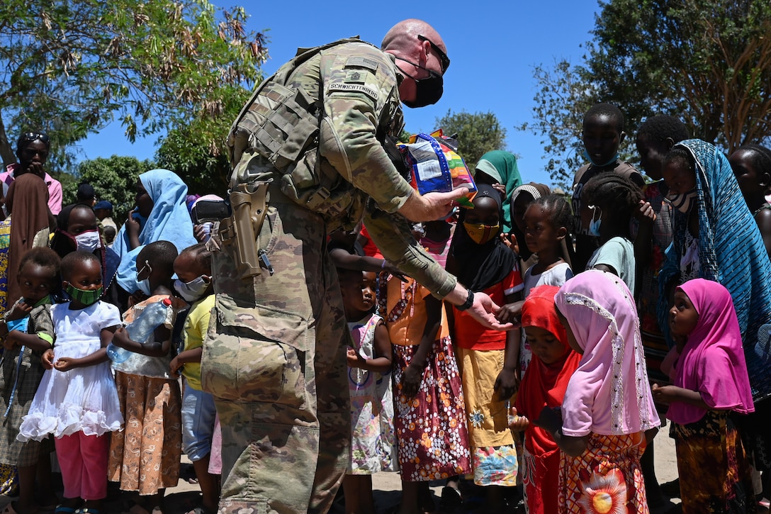 A soldier hands out candy to a group of children.