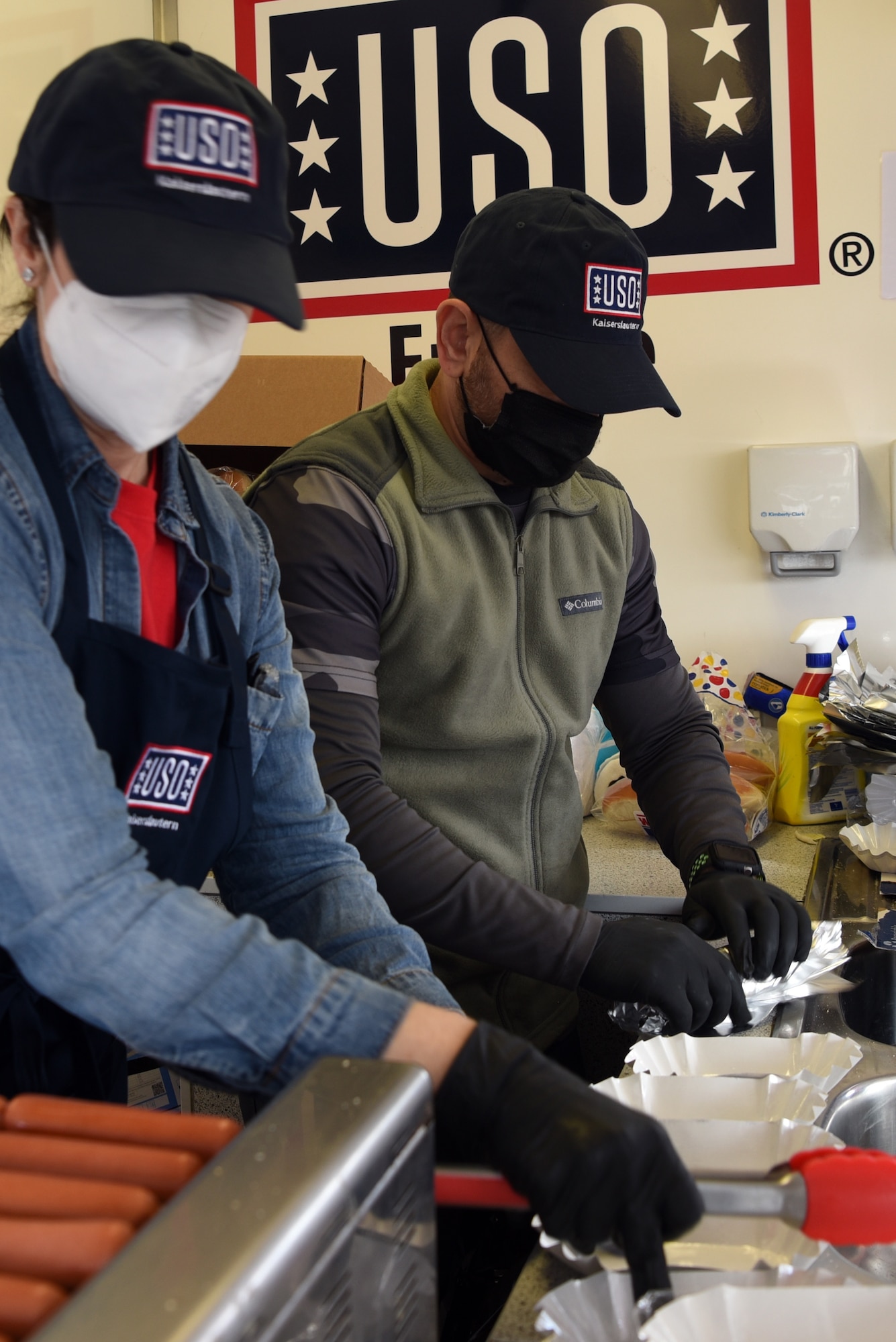 Leslie Champion, USO volunteer and U.S. Air Force spouse, left, and Levoun Ohan, USO volunteer and active duty service member, prepare hot dogs for members of the 86th Logistics Readiness Group.