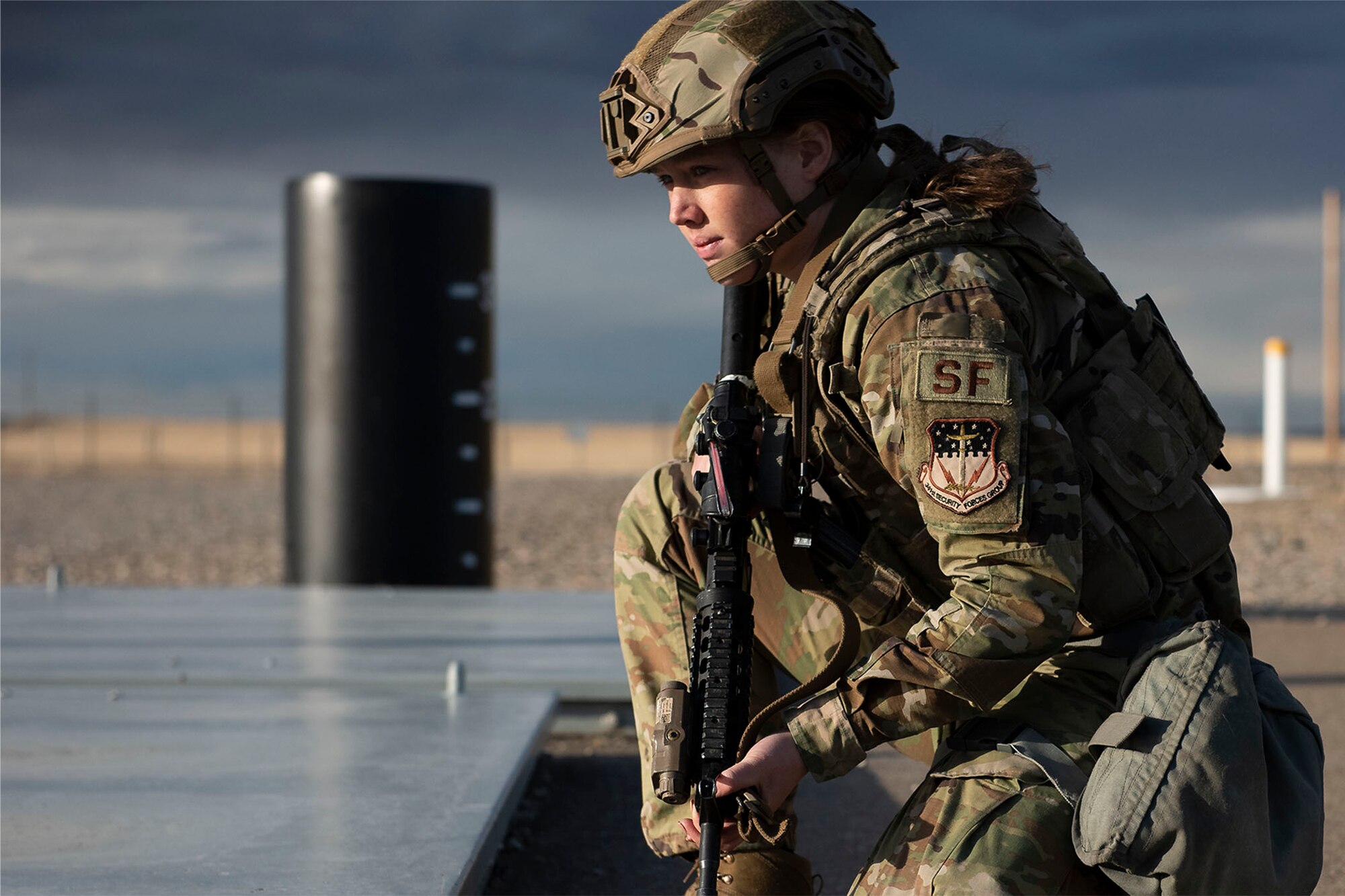 A female defender takes a knee while on duty while holding a rifle at a launch facility.