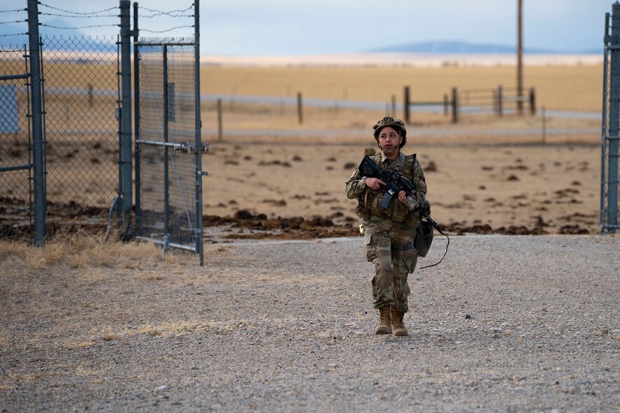 Defender walks towards the camera from the gate of the launch facility towards the center of the launch facility.