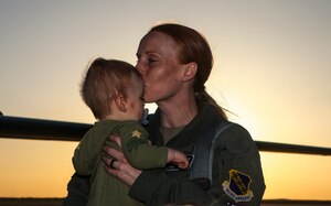 A 9th Expeditionary Bomb Squadron pilot kisses her son after returning from a Bomber Task Force Europe deployment in Norway at Dyess Air Force Base, Texas, March 23, 2021. The training missions that the 9th EBS conducted during the deployment enabled them to prepare for potential future operations. (U.S. Air Force photo by Staff Sgt. David Owsianka)