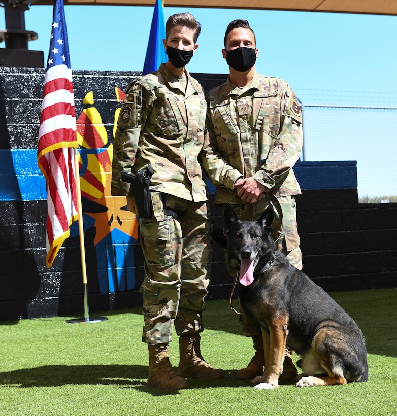 Maj. Kimberly Guest, left, 56th Security Forces Squadron commander, and Tech. Sgt. Zackery Hons, 56th SFS military working dog handler, honor Rango, 56th SFS MWD, as he retires March 19, 2021 at Luke Air Force Base, Arizona. Rango, an 8-year old Czech German Shepherd, leaves behind the legacy of taking first place at the 2019 Desert Dog Trials for narcotic detection, beating 70 other K-9 teams, and will retire into the care of his former handler. As the Air Force prepares to retire a MWD, the dog’s handler can request to adopt the dog enabling it to live the remainder of its life as a family member. Boss and Rango will retire and live at home with their respective handler. (U.S. Air Force photo by Staff Sgt. Amber Carter)