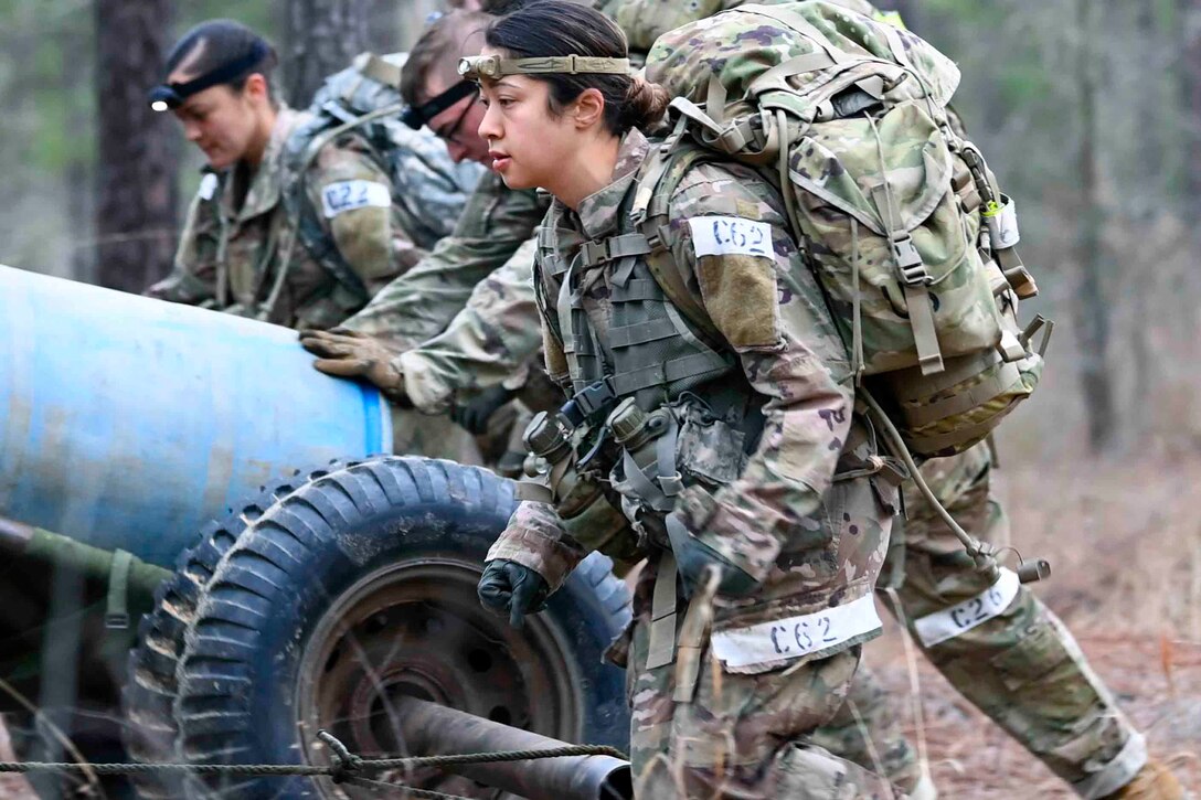 Soldiers move through a wooded area.