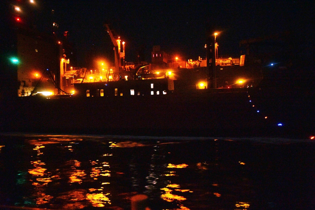 A ship travels through waters at night.