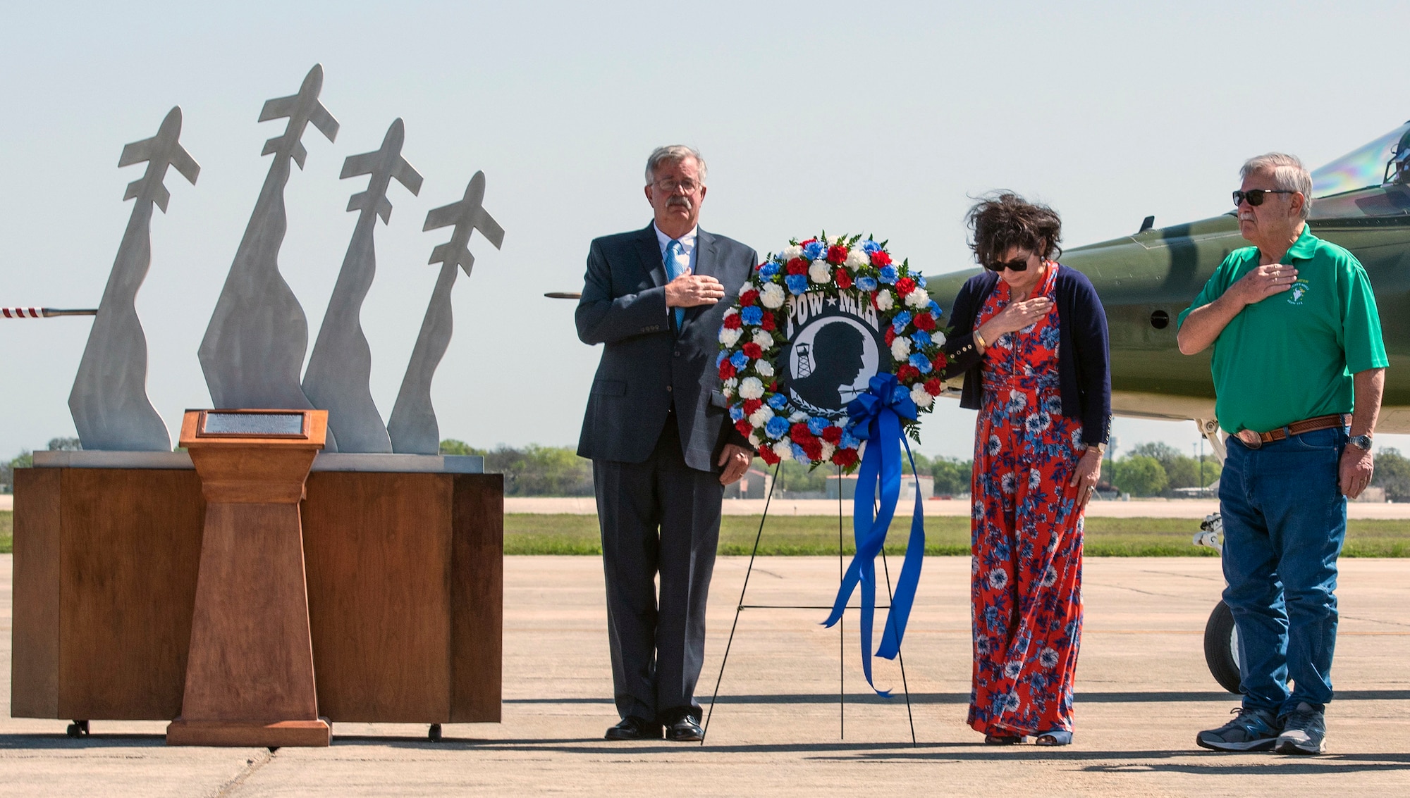 Former prisoners of war retired Capt. Gregg Hanson (left) and retired Maj. Richard Bates (right) are joined by Janine Sijan in a moment of silence to honor prisoners of war during the Freedom Flyers wreath-laying ceremony at Joint Base San Antonio-Randolph March 26. Janine is the sister of Capt. Lance P. Sijan, a Medal of Honor recipient who lost his life as a POW in Vietnam. The 560th Flying Training Squadron holds the annual Freedom Flyers Reunion, which gives prisoners of war a chance to take their final flights and honor those who are unable to. This year was the 47th Freedom Flyers Reunion.