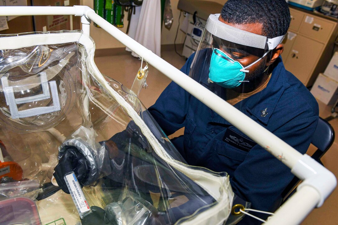 A sailor wearing a face mask and gloves tests a nasal swab sample.