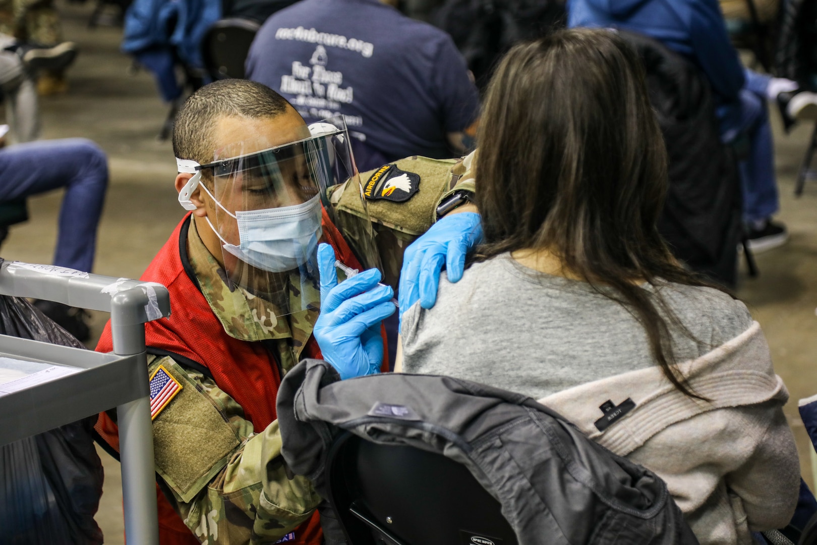 A U.S. Army combat medic talks with a community member while administering a COVID vaccine.