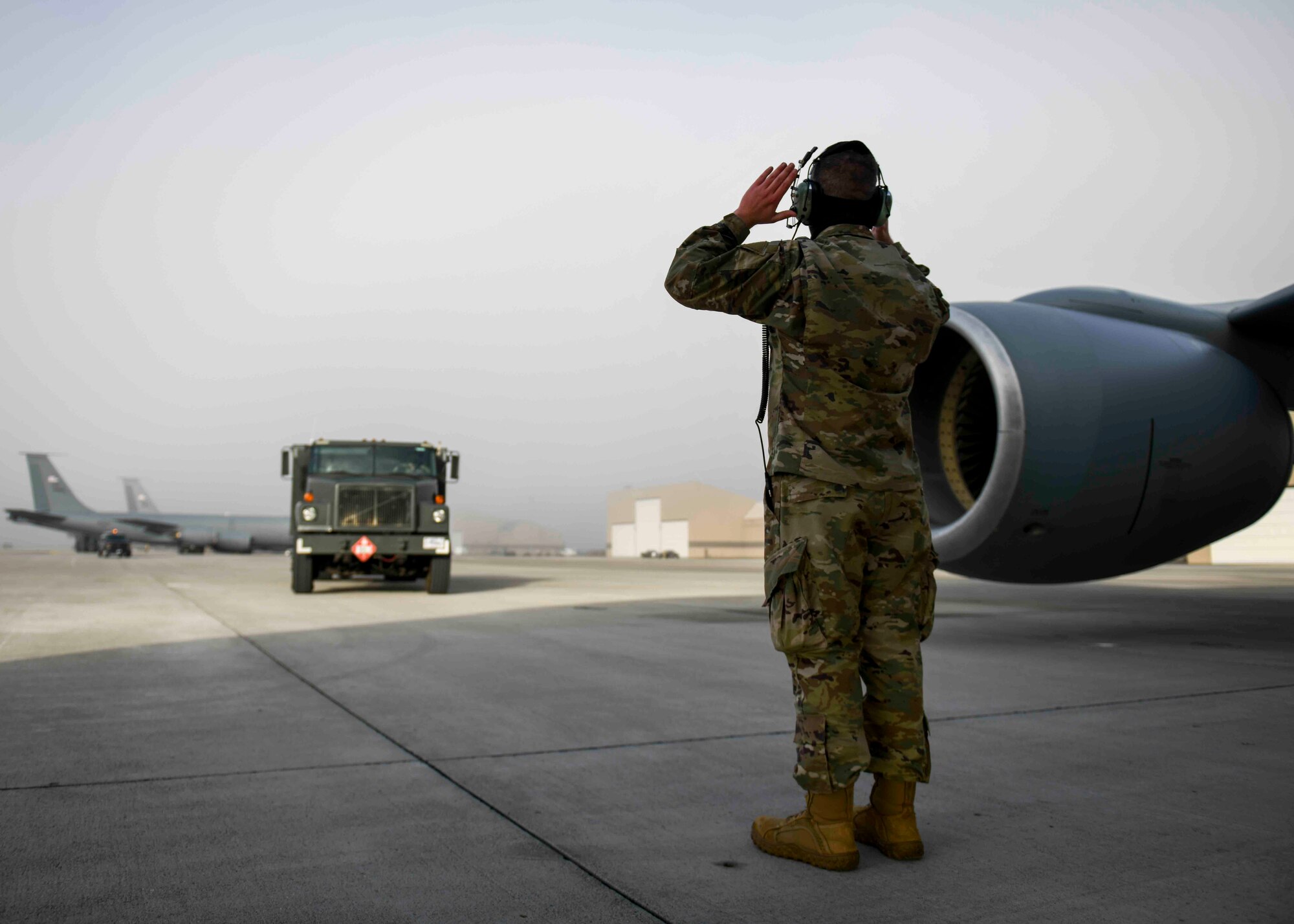 A 92nd Maintenance Squadron Airman guides a fuels truck toward a KC-135 Stratotanker in preparation for hot pit refueling on Fairchild Air Force Base, Washington, March 25, 2021. Being the first base in the Continental U.S. to bring the hot pit refueling capability CONUS, this showcases the innovation and preparedness Team Fairchild and the Air Mobility Command possess and implements. (U.S. Air Force photo by Airman 1st Class Kiaundra Miller)
