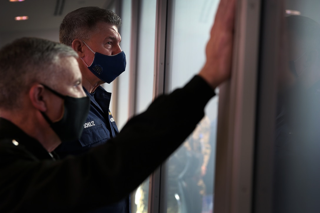 Army Gen. Paul M. Nakasone, U.S. Cyber Command commander and National Security Agency director, and Coast Guard Adm. Karl L. Schultz, U.S. Coast Guard commandant, observe activity in the USCYBERCOM Joint Operations Center.