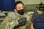 Michigan Army National Guard Pfc. Julio Mendez, a combat medic, administers the COVID-19 vaccine to a resident at the county fairgrounds in Adrian, Michigan, March 19, 2021. Michigan National Guard members are working with local health care officials to vaccinate Michiganders.