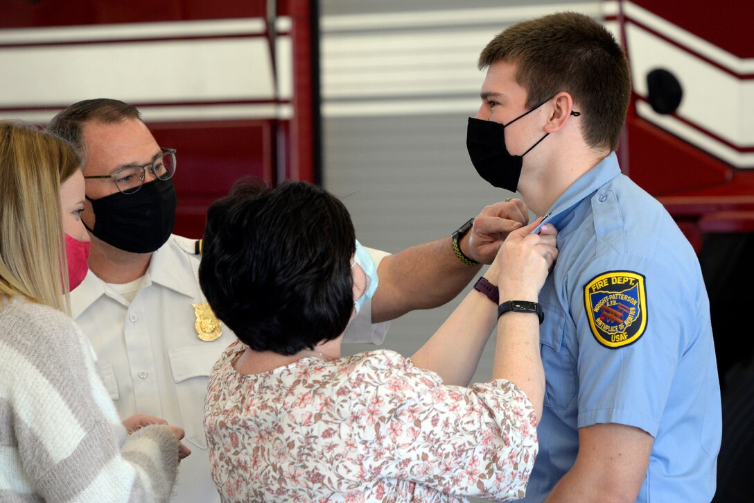 Ryan Hartman, a new Air Force firefighter with the 788th Civil Engineer Squadron, is pinned on by his mother, Vicki Hartman, and Fire Chief Jacob King during a promotion ceremony at Wright-Patterson Air Force Base, Ohio on Monday, March 29, 2021.