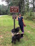 Kathy stands near a sign with two dogs