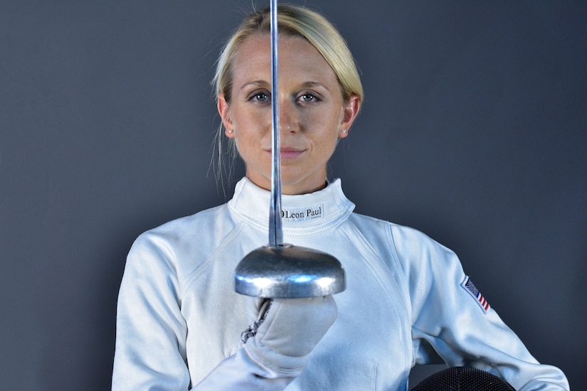 A woman holds a fencing sword.