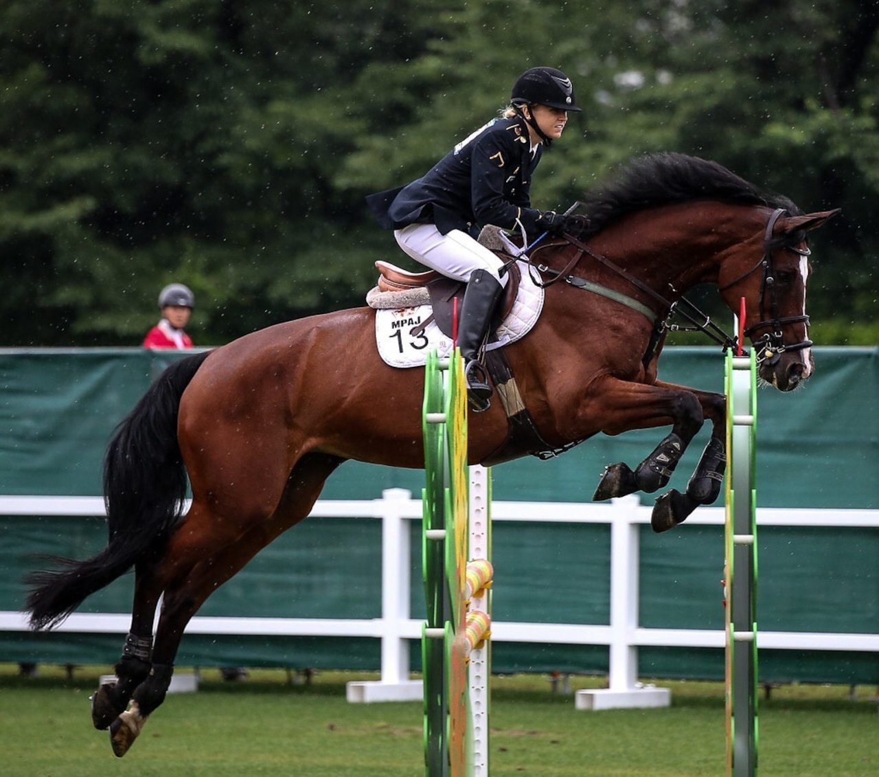 A woman rides a leaping horse.