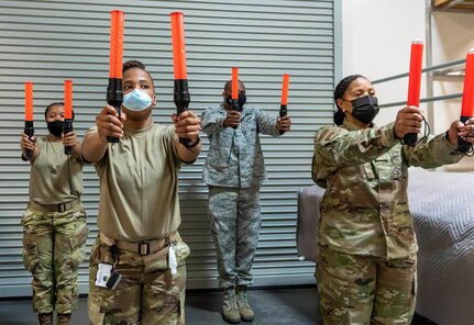 Airman practice marshalling during the Force Support Contingency Training-Mortuary course at Dover Air Force Base, Delaware, Mar. 23, 2021. During a dignified transfer, an Air Force Mortuary Affairs Operations member is responsible for marshaling the fallen service member’s family’s transport vehicle into place. (U.S. Air Force photo by Jason Minto)