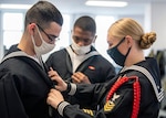 Petty Officer 1st Class Sarah Minnick, a recruit division commander, corrects the neckerchief of one of her recruits inside their compartment of the USS Kearsarge recruit barracks at Recruit Training Command.