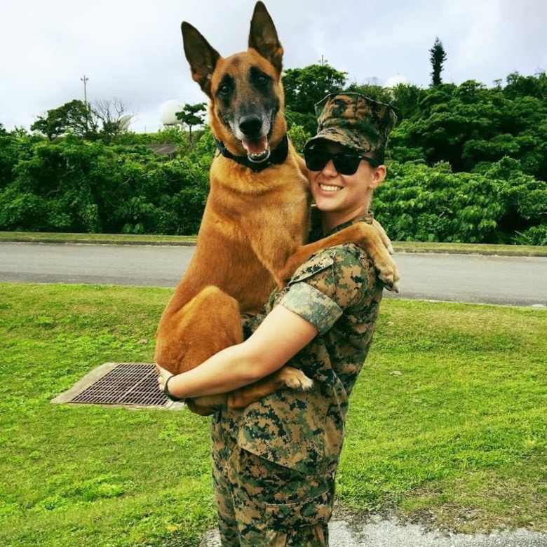 A Marine poses for a photo next to a dog.