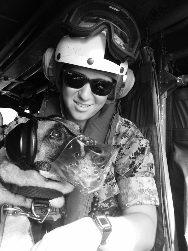 A Marine poses for a photo with a dog.