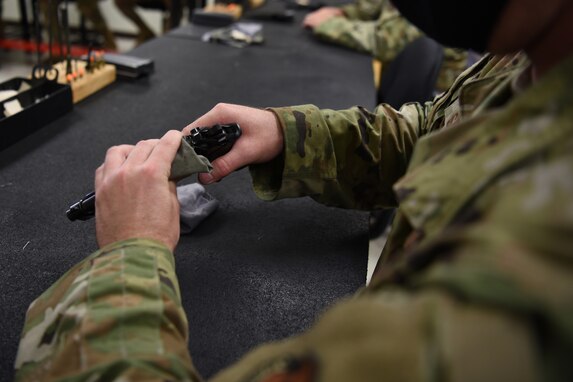 U.S. Air Force Tech. Sgt. Terry Snyder, 17th Communications Squadron radio frequency noncommissioned officer in charge, cleans a firearm during the Shooting in Excellence competition at the firing range, on Goodfellow Air Force Base, Texas, March 30, 2021. Snyder cleaned the firearm to remove any access carbon buildup that may have accumulated during its use, which protects the equipment from damage.  (U.S. Air Force Senior photo by Airman Abbey Rieves)
