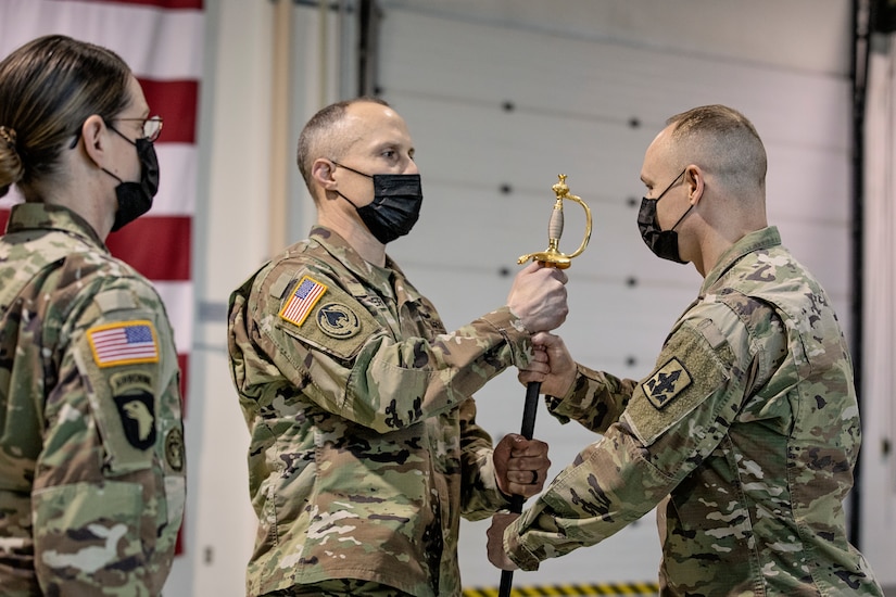 Col. Tim Brower (center), commander of 38th Troop Command, Alaska Army National Guard, passes the ceremonial scepter to Command Sgt. Maj. John Phlegar (right) during a change of responsibility ceremony on Joint Base Elmendorf-Richardson, Alaska, March 30. Phlegar assumed the role as the senior enlisted leader from Command Sgt. Maj. Maureen Meehan (left), making Phlegar the senior noncommissioned officer in charge of the brigade. (U.S. Army National Guard photo by Edward Eagerton)