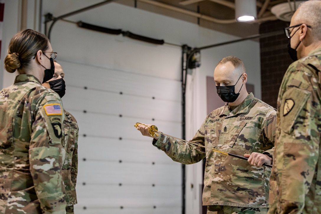 Command Sgt. Maj. John Phlegar (center), the incoming senior noncommissioned officer in charge, 38th Troop Command, Alaska Army National Guard, inspects the ceremonial scepter during a change of responsibility ceremony on Joint Base Elmendorf-Richardson, Alaska, March 30. Phlegar assumed the role as the senior enlisted leader from Command Sgt. Maj. Maureen Meehan (left), making Phlegar the senior noncommissioned officer in charge of the brigade. (U.S. Army National Guard photo by Edward Eagerton)