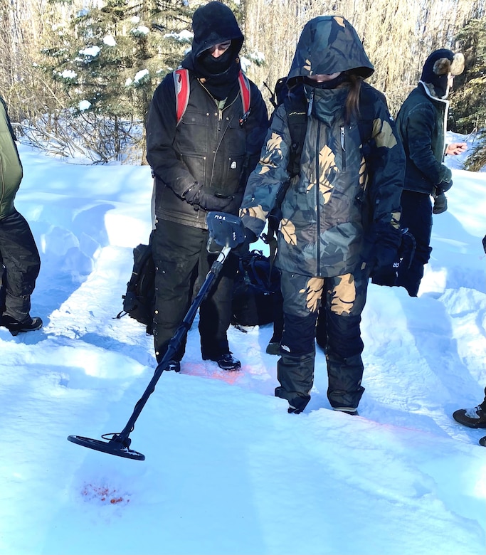 Staff Sgt. Jaimie Doney, 673rd Security Forces Squadron, and Special Agent Mike O'Hara, Office of Special Investigations, Detachment 631, use a metal detector to search for a bullet casing buried three feet in the snow. This was part of a snow-based exercise held at Joint Base Elmendorf-Richardson, Alaska, March 18-19, to test operational readiness in winter environments (U.S. Air Force photo by 1st Lt. Ashlyn K. Paulson).