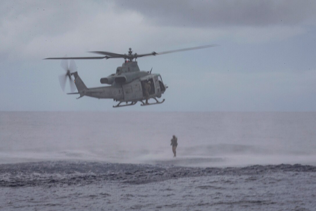 A Marine jumps from a helicopter into a body of water.