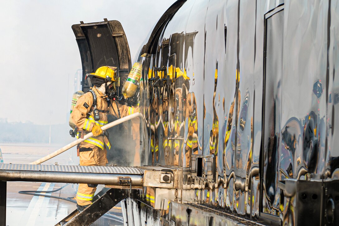 A service member puts out a fire on an aircraft.