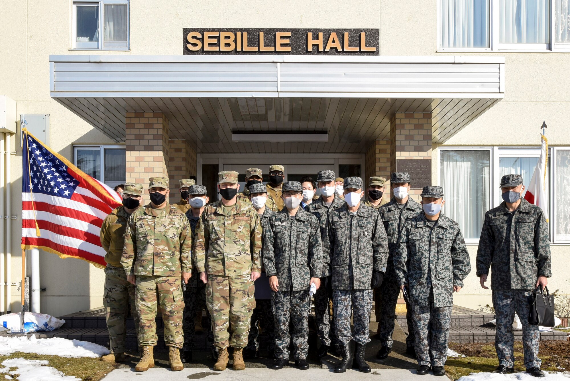 U.S. and Japanese Airmen pose for a group photo after touring the 35th Fighter Wing's unaccompanied housing campus at Misawa Air Base, Japan, Feb. 26, 2021. U.S. Air Force Col. William Bernhard, 35th Mission Support Group commander, hosted Japan Air Self-Defense Force Col. Kato Fumihiko, 3rd Air Wing vice commander, and other JASDF leaders on the tour as they learned about the 35th FW's quality of life standards, room layouts, and other management techniques used to provide a quality living standard for unaccompanied Airmen. (U.S. Air Force photo by Tech. Sgt. Timothy Moore)