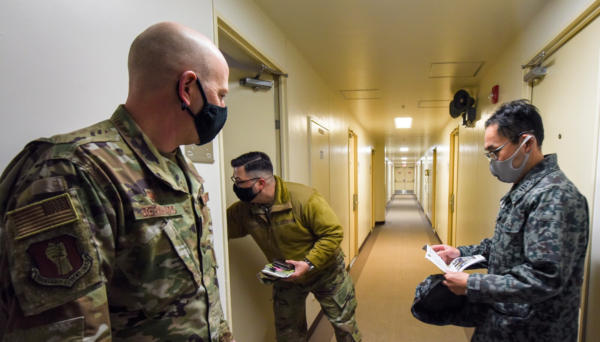 U.S. Air Force Master Sgt. William Castro, 35th Civil Engineer Squadron Unaccompanied Housing superintendent, opens a door to a dormitory room for Col. William Bernhard, 35th Mission Support Group commander, and Japan Air Self-Defense Force Col. Kato Fumihiko, 3rd Air Wing vice commander, during a tour of the unaccompanied housing dormitory campus at Misawa Air Base, Japan, Feb. 26, 2021. Bernhard hosted Fumihiko and other JASDF leaders on the tour as they learned about the 35th Fighter Wing's quality of life standards, room layouts, and other management techniques used to provide a quality living standard for unaccompanied Airmen. (U.S. Air Force photo by Tech. Sgt. Timothy Moore)