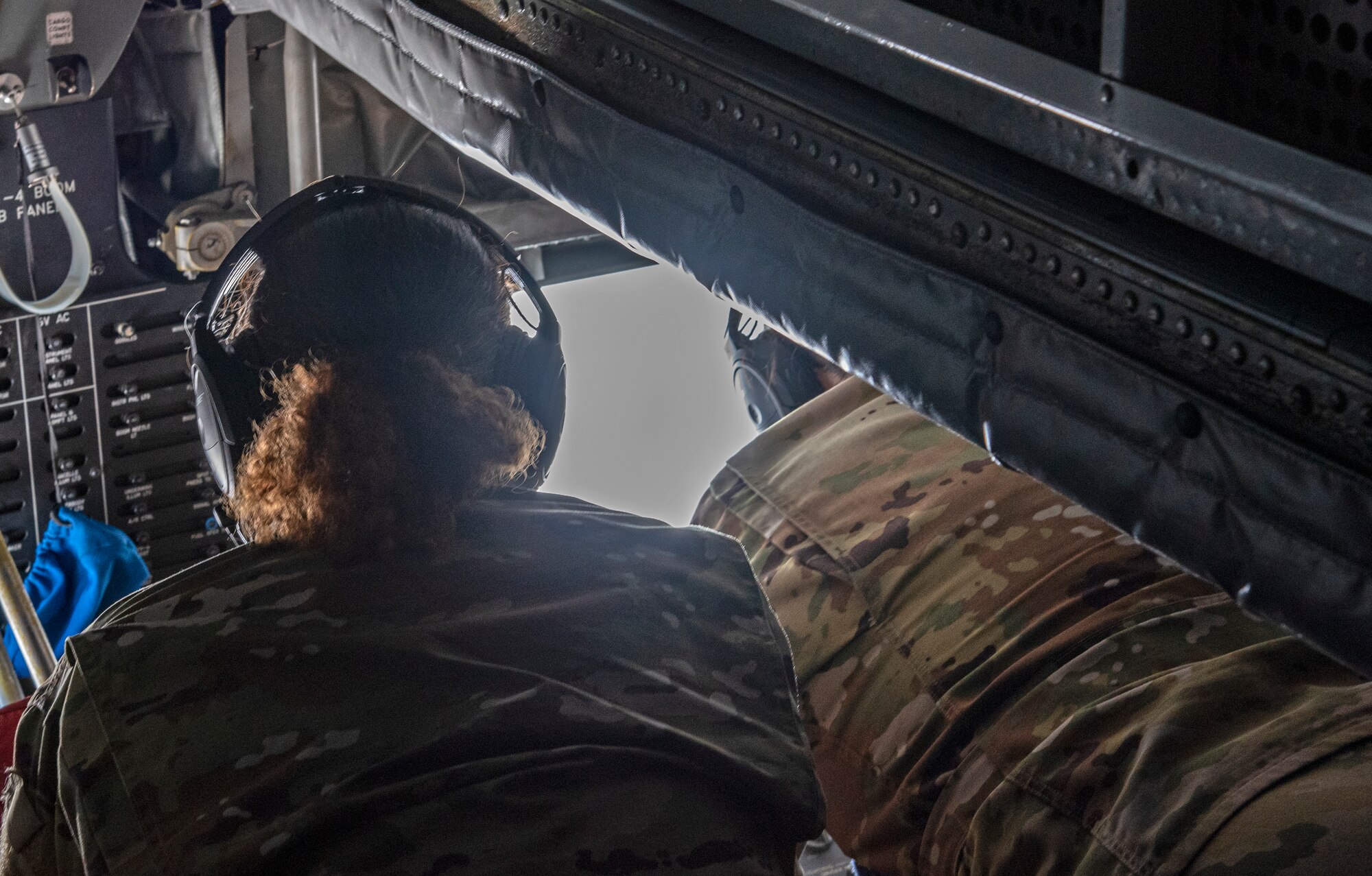 U.S. Air Force Chief Master Sgt. Shae Gee, 6th Air Refueling Wing command chief looks on as Airman Keegan Salas, a 50th Air Refueling Squadron boom operator, operates the controls on the boom of a KC-135 Stratotanker aircraft, March 30, 2021.