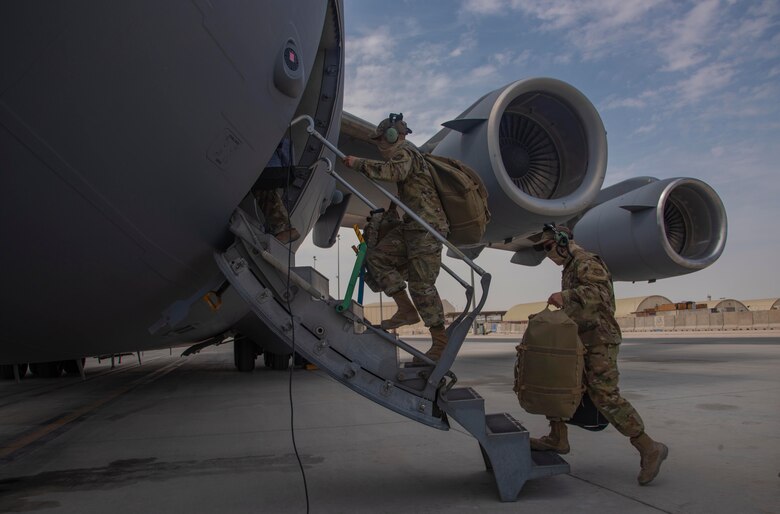 Aircrew assigned to Al Udeid Air Base, Qatar, carry their gear into a C-17 Globemaster III assigned to Joint Base Charleston, South Carolina, April 27, 2021, at Al Udeid AB.