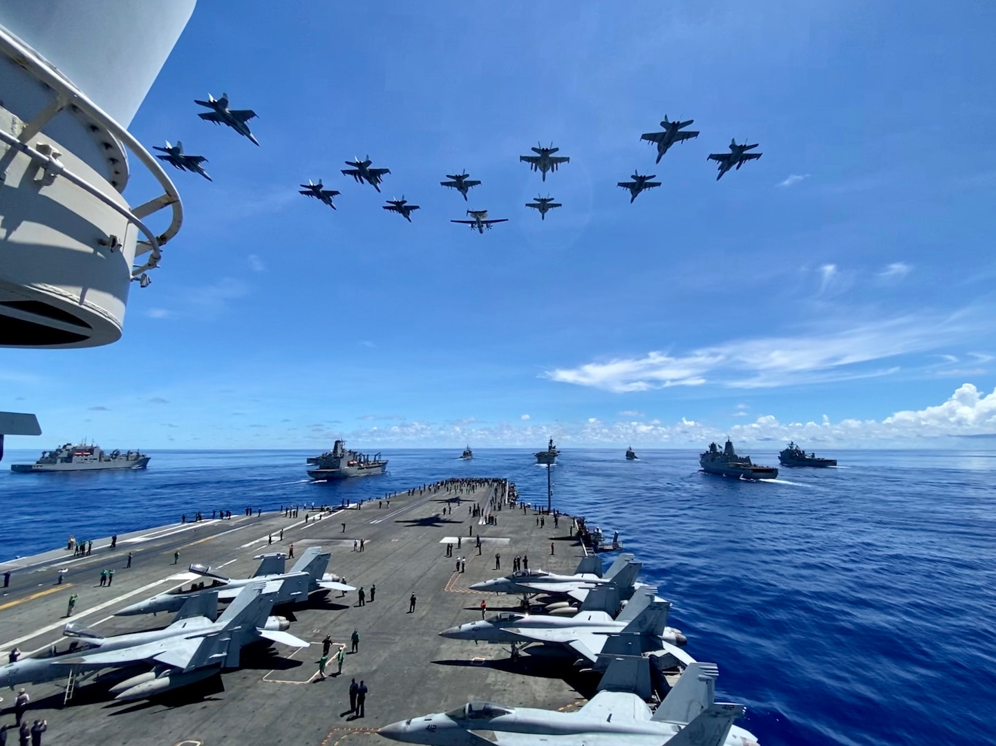 IMAGE: U.S. Navy warships steam in formation while E/A-18G Growlers, FA-18E Super Hornets and an E-2D Hawkeye from Carrier Air Wing (CVW) 5 fly over in support of Valiant Shield 2020. Naval Surface Warfare Center Dahlgren Division (NSWCDD) engineers designed and patented a new modeling and simulation tool known as “OSM” for Orchestrated Simulation through Modeling that is impacting technical programs, wargames and military exercises such as Valiant Shield. OSM is a new framework allowing scientists, warfighters, and college students to model ideas and develop wargaming scenarios seamlessly. The Modeling and Simulation Toolbox (MAST) architecture – built on the OSM framework – offers a human-in-the-loop wargaming capability that positively impacted and adjudicated live events and military exercises – including Valiant Shield and Northern Edge. “The opportunities and possibilities for analysis using OSM and MAST are unlimited,” said Mike Maldonado, NSWCDD Modeling and Simulation Branch deputy program manager. “The framework is built for speed and provides anyone with the capability to model and test an idea quickly – in minutes – to see if it’s going in the right direction.” Pictured from left: USNS Sacagawea (T-AKE 2), USS Germantown (LSD 42), USNS John Ericsson (T-AO 194), USS Antietam (CG 54), USS Ronald Reagan (CVN 76), USS America (LHA 6), USS Shiloh (CG 67), USS New Orleans (LPD 18), and USS Comstock (LSD 45).
