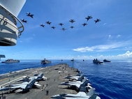 IMAGE: U.S. Navy warships steam in formation while E/A-18G Growlers, FA-18E Super Hornets and an E-2D Hawkeye from Carrier Air Wing (CVW) 5 fly over in support of Valiant Shield 2020. Naval Surface Warfare Center Dahlgren Division (NSWCDD) engineers designed and patented a new modeling and simulation tool known as “OSM” for Orchestrated Simulation through Modeling that is impacting technical programs, wargames and military exercises such as Valiant Shield. OSM is a new framework allowing scientists, warfighters, and college students to model ideas and develop wargaming scenarios seamlessly. The Modeling and Simulation Toolbox (MAST) architecture – built on the OSM framework – offers a human-in-the-loop wargaming capability that positively impacted and adjudicated live events and military exercises – including Valiant Shield and Northern Edge. “The opportunities and possibilities for analysis using OSM and MAST are unlimited,” said Mike Maldonado, NSWCDD Modeling and Simulation Branch deputy program manager. “The framework is built for speed and provides anyone with the capability to model and test an idea quickly – in minutes – to see if it’s going in the right direction.” Pictured from left: USNS Sacagawea (T-AKE 2), USS Germantown (LSD 42), USNS John Ericsson (T-AO 194), USS Antietam (CG 54), USS Ronald Reagan (CVN 76), USS America (LHA 6), USS Shiloh (CG 67), USS New Orleans (LPD 18), and USS Comstock (LSD 45).