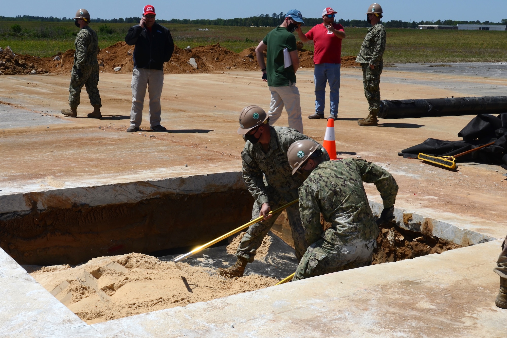 U.S. Navy engineers from Navy Mobile Construction Battalion 133, Gulfport, Mississippi, fill in an excavated hole during an Expedient and Expeditionary Airfield Damage Repair (E-ADR) Joint Capability Technology Demonstration at McEntire Joint National Guard Base, South Carolina, April 22, 2021. The demonstration field tests the “just enough, just-in-time” repair capability on a decommissioned runway at McEntire Joint National Guard Base. The Department of Defense’s E-ADR concept uses local materials and minimal personnel and equipment in order to expedite a temporary runway repair. (U.S. Air National Guard photo by Lt. Col. Jim St.Clair, 169th Fighter Wing Public Affairs)