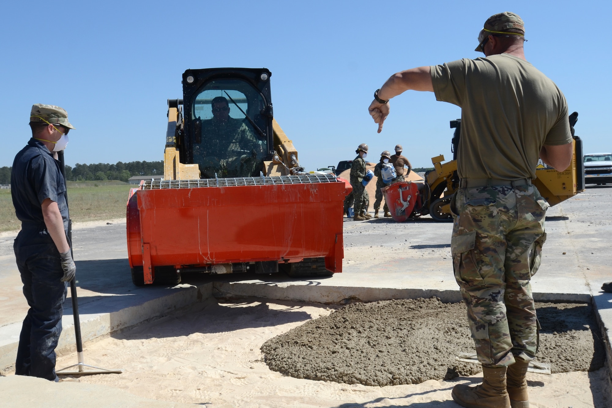 U.S. Air Force Master Sgt. Daniel Jennings (right) and Senior Airman David Poynter, 169th Civil Engineer Squadron heavy equipment operators, place poured concrete into a repaired section of runway during an Expedient and Expeditionary Airfield Damage Repair (E-ADR) Joint Capability Technology Demonstration at McEntire Joint National Guard Base, South Carolina, April 22, 2021. The demonstration simulates the rapid repair of a battle damaged runway. (U.S. Air National Guard photo by Lt. Col. Jim St.Clair, 169th Fighter Wing Public Affairs)