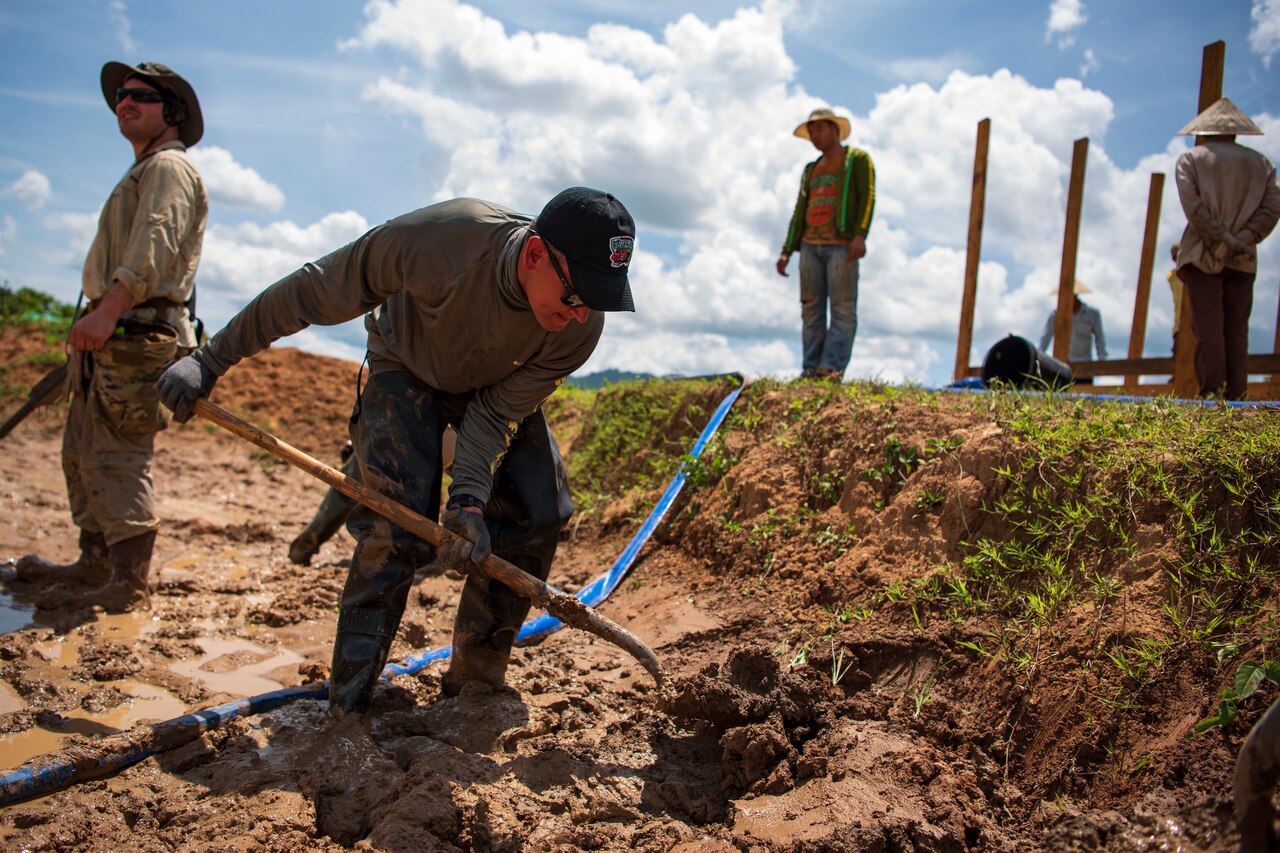 A man uses a shovel to dig in the ground.