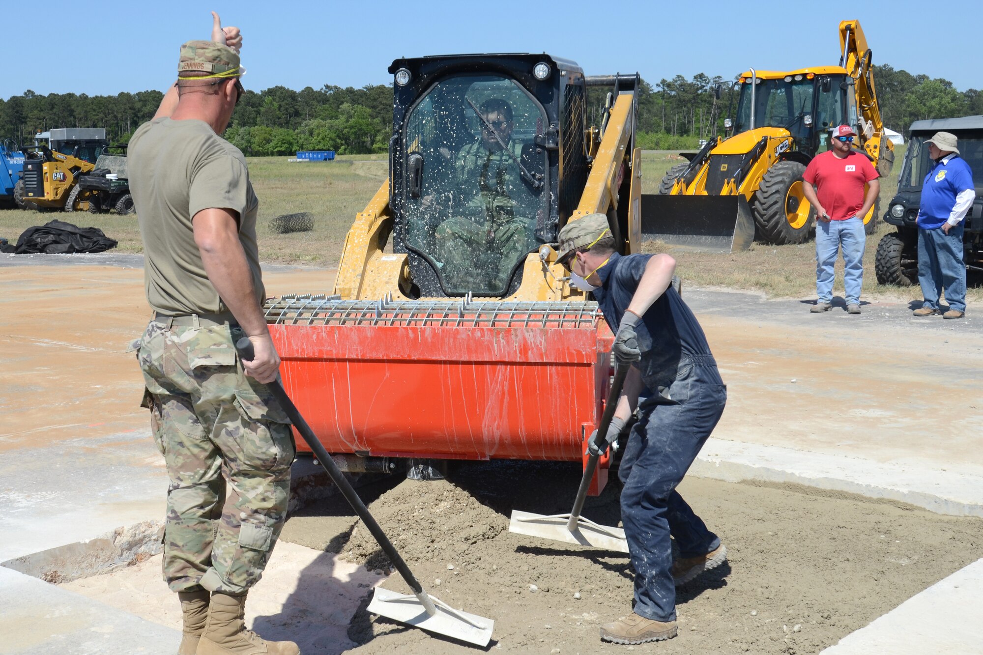 U.S. Air Force Master Sgt. Daniel Jennings and Senior Airman David Poynter, 169th Civil Engineer Squadron heavy equipment operators, place poured concrete into a repaired section of runway during an Expedient and Expeditionary Airfield Damage Repair (E-ADR) Joint Capability Technology Demonstration at McEntire Joint National Guard Base, South Carolina, April 22, 2021. The demonstration simulates the rapid repair of a battle damaged runway. (U.S. Air National Guard photo by Lt. Col. Jim St.Clair, 169th Fighter Wing Public Affairs)