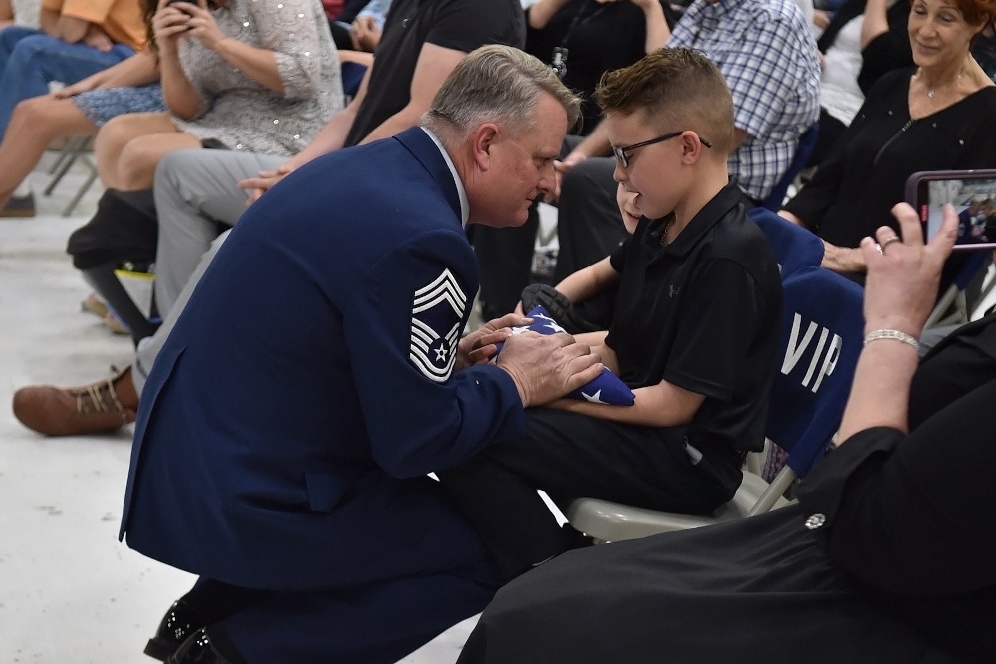 Chief Master Sgt. Chad Weisend hands off his folded flag to his grandson Karston Black during his retirement ceremony held at Grissom Air Reserve Base, Ind., May 1, 2021. Weisend retired as after 36 years of service. (U.S. Air Force Photo/ Tech. Sgt. Jami K. Lancette)