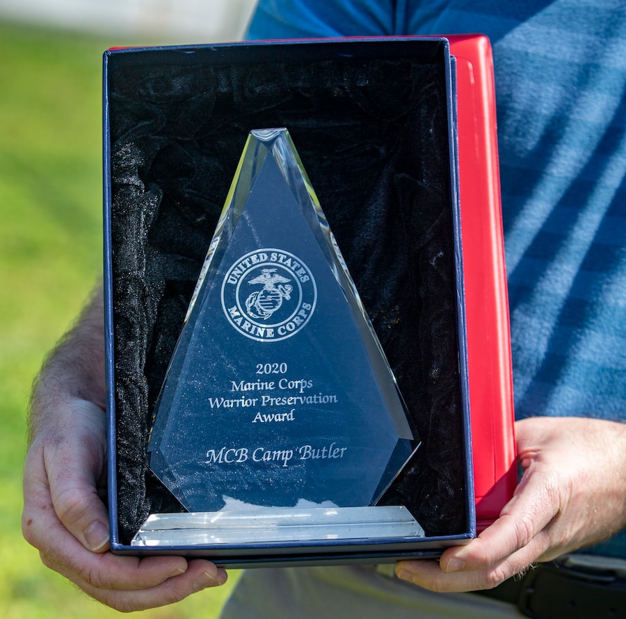 An Installation Safety Office employee displays the Marine Corps Warrior Preservation Award on Camp Foster, Okinawa, Japan, April 26, 2021. The 2020 Marine Corps Ground Safety Awards recognizes commands and individuals for their significant contributions and accomplishments in the field of safety and mishap prevention during the fiscal year. (U.S. Marine Corps photo by Cpl. Karis Mattingly)