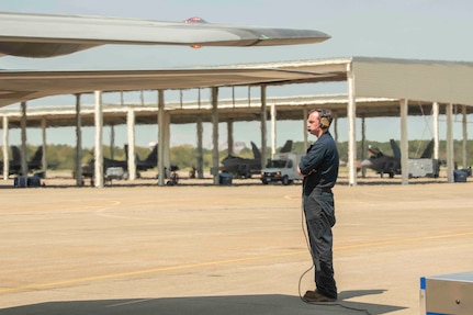 A crew chief looks on as an F-22 Raptor prepares to take flight